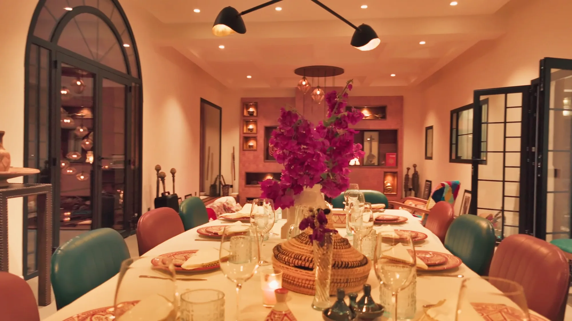 Villa Yemna riad dining table set in Marrakech with fuchsia bougainvillea centerpiece, crystal glassware and Moroccan tableware.