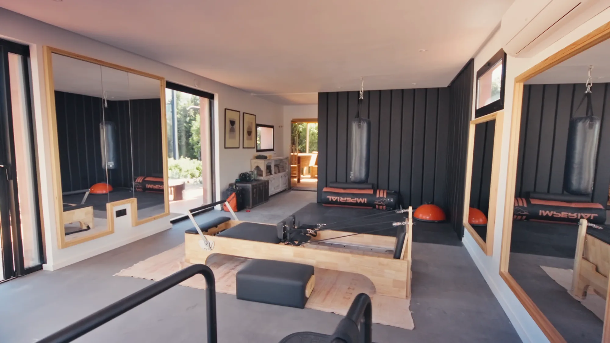Private gym at Villa Yemna in Marrakech with Pilates Reformer machine, boxing bags, Bosu balance trainers and wall mirrors.