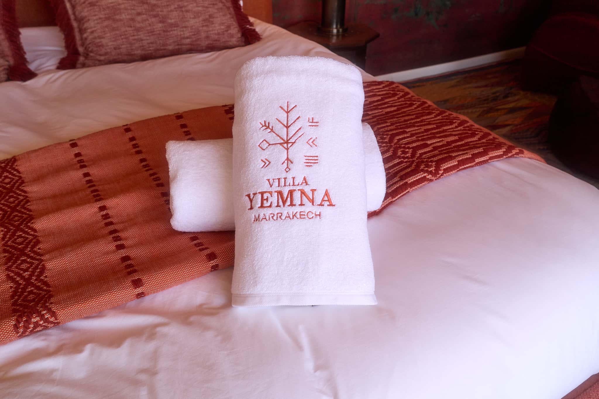 Detail of embroidered Villa Yemna towels placed on the bed in the Suite Oukaimeden.