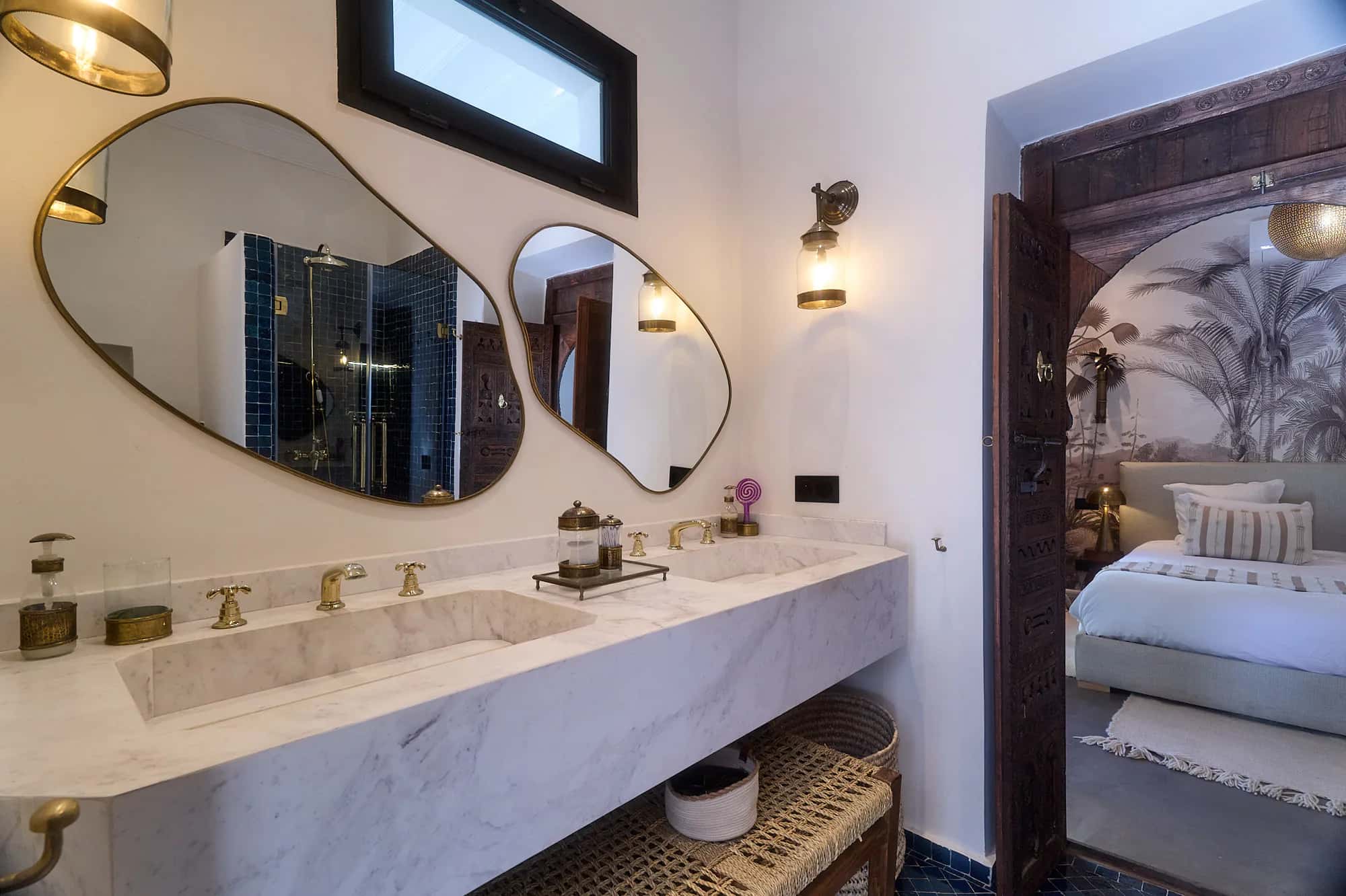 Suite Imsouane bathroom at Villa Yemna with twin organic mirrors, a marble vanity, and a view toward the bedroom.