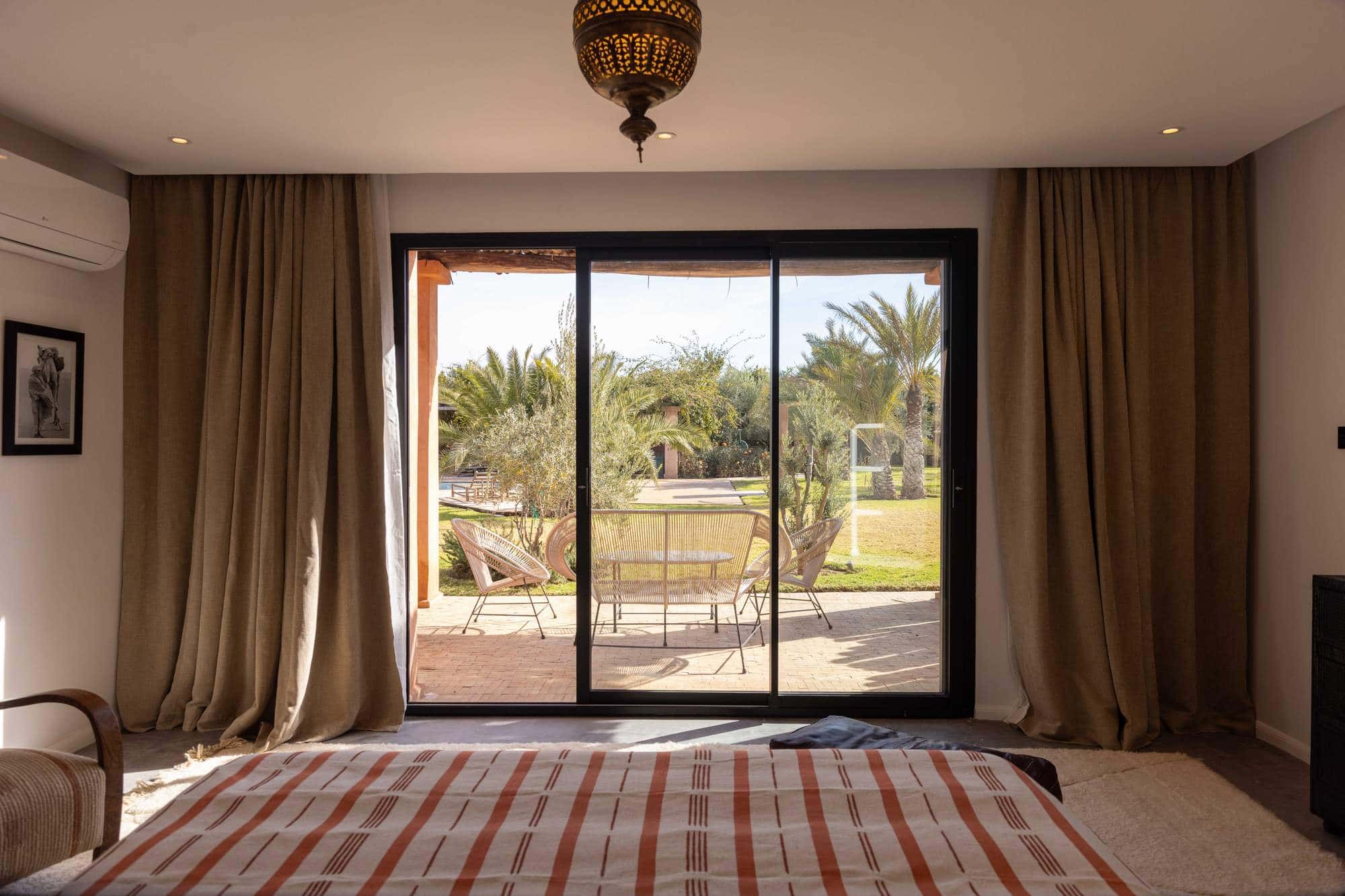 Ourika Suite at Villa Yemna in Marrakech, bedroom with view over the palm-tree terrace.