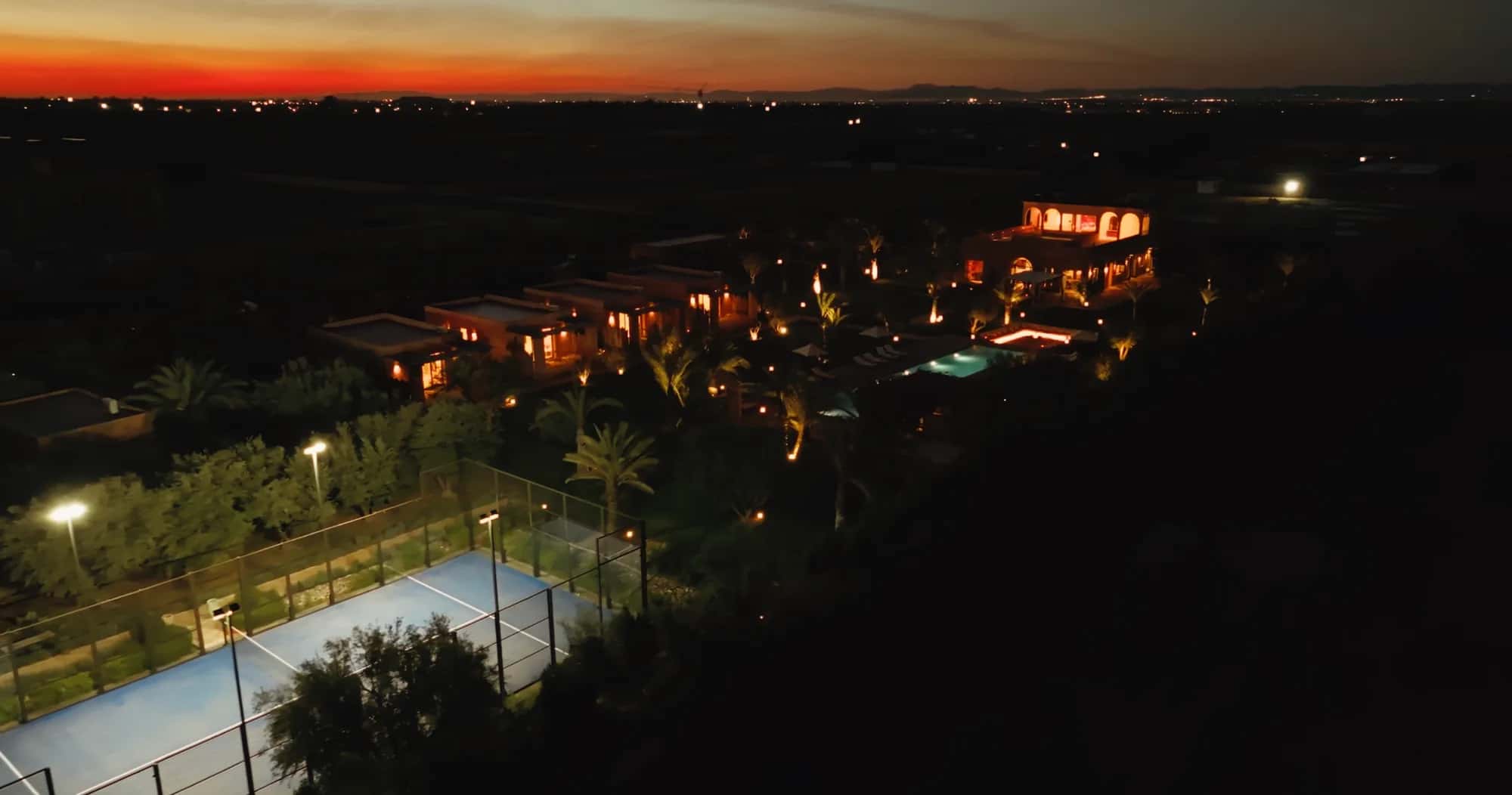 Night drone view of the Villa Yemna estate and padel court at sunset.