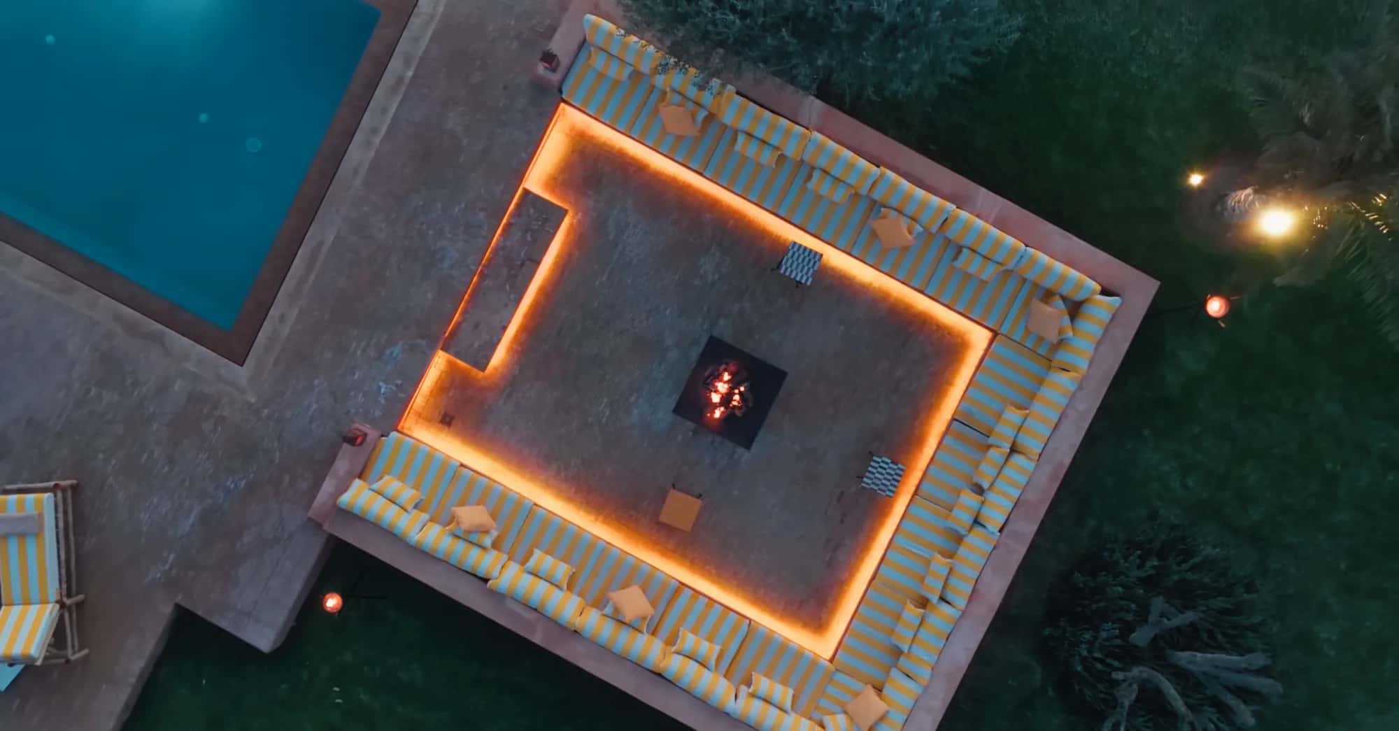 Night drone view of the pool and illuminated fire pit lounge at Villa Yemna.