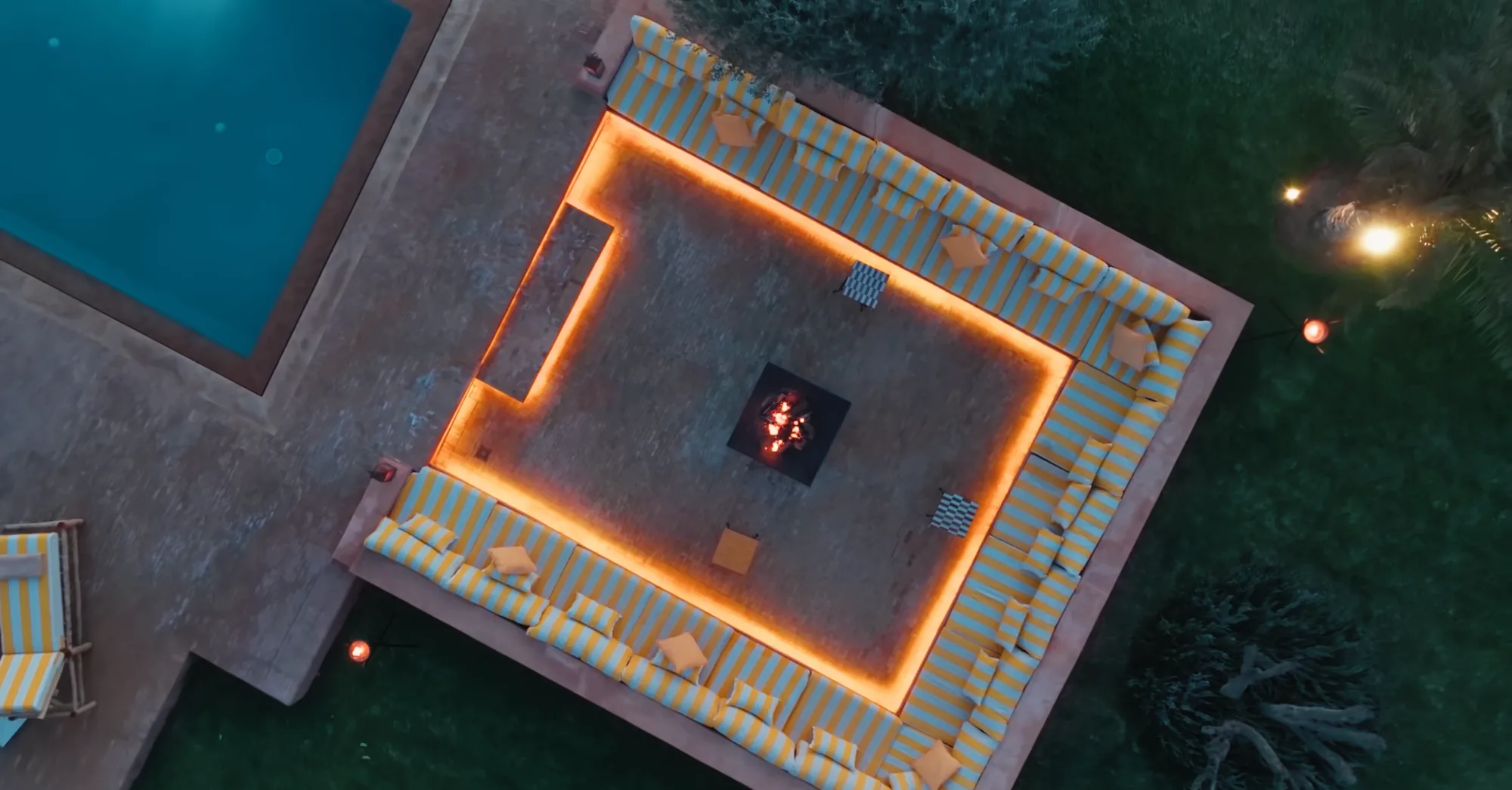 Night drone view of the pool and illuminated fire pit lounge at Villa Yemna.